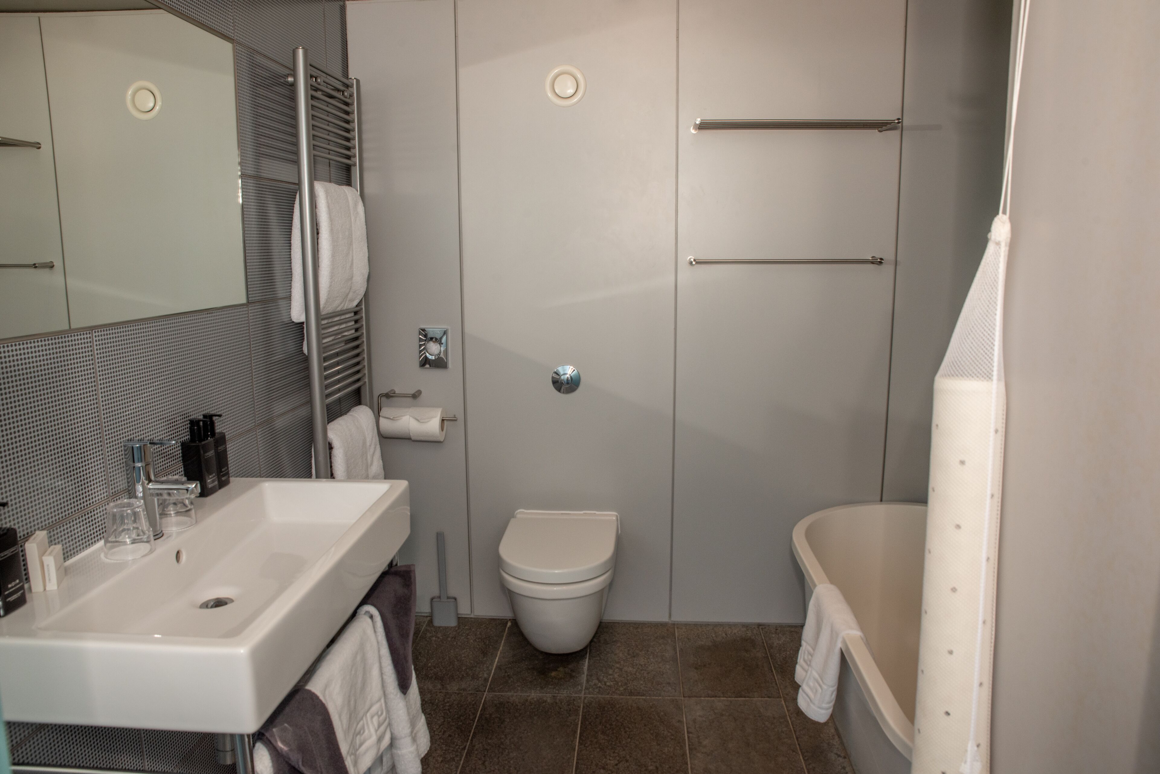 A modern bathroom with a sink, toilet, and bathtub.