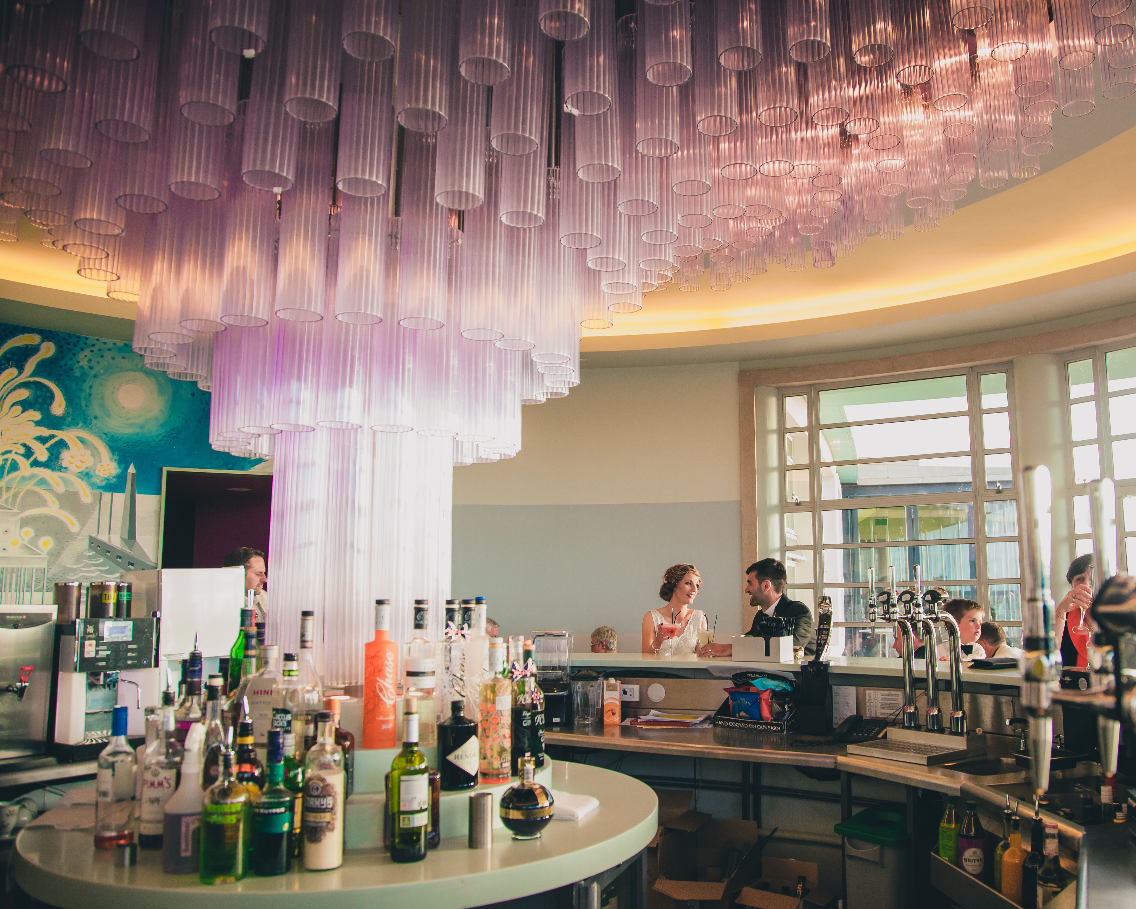 A bar area with a variety of bottles, a counter, and a large window.