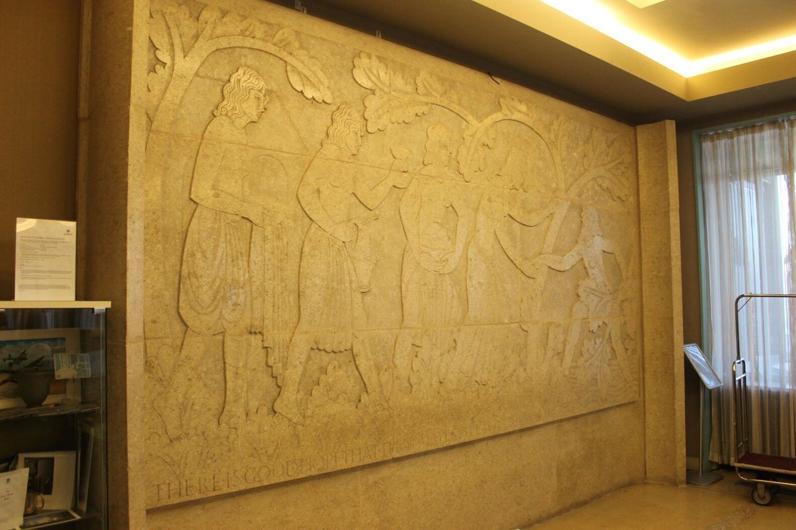 Een grote muur met een reliëfbeeldhouwwerk waarop figuren en bladeren zijn afgebeeld.