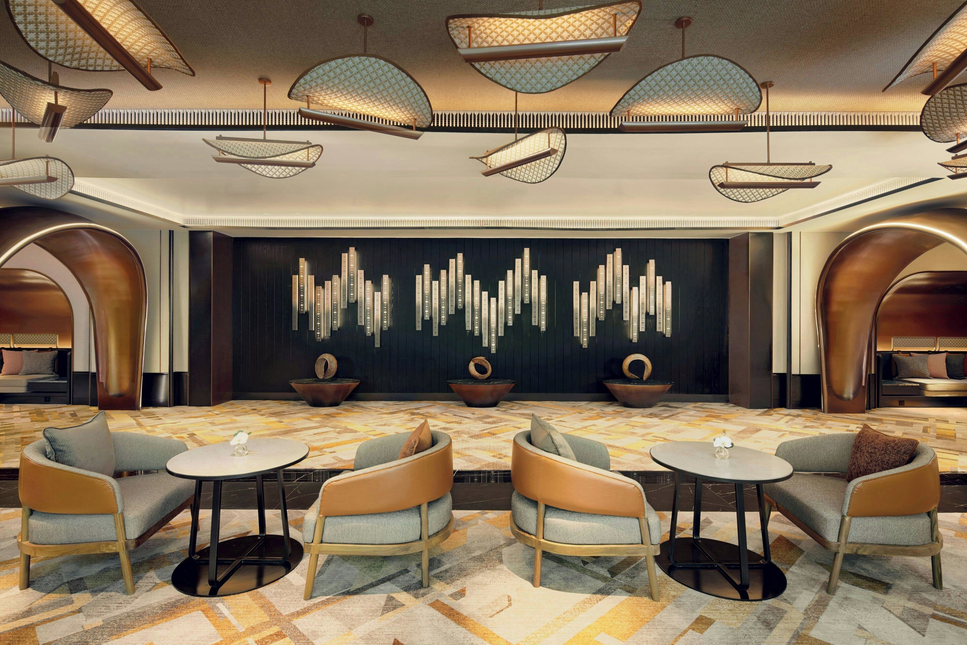 A modern lounge area with contemporary furniture, a patterned carpet, and a decorative wall with vertical elements.