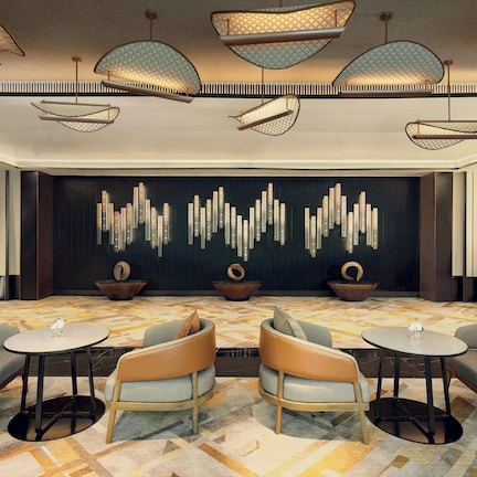 A modern lounge area with contemporary furniture, a patterned carpet, and a decorative wall with vertical elements.