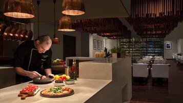 A chef preparing food in a modern kitchen with copper fixtures and a wine cellar in the background.
