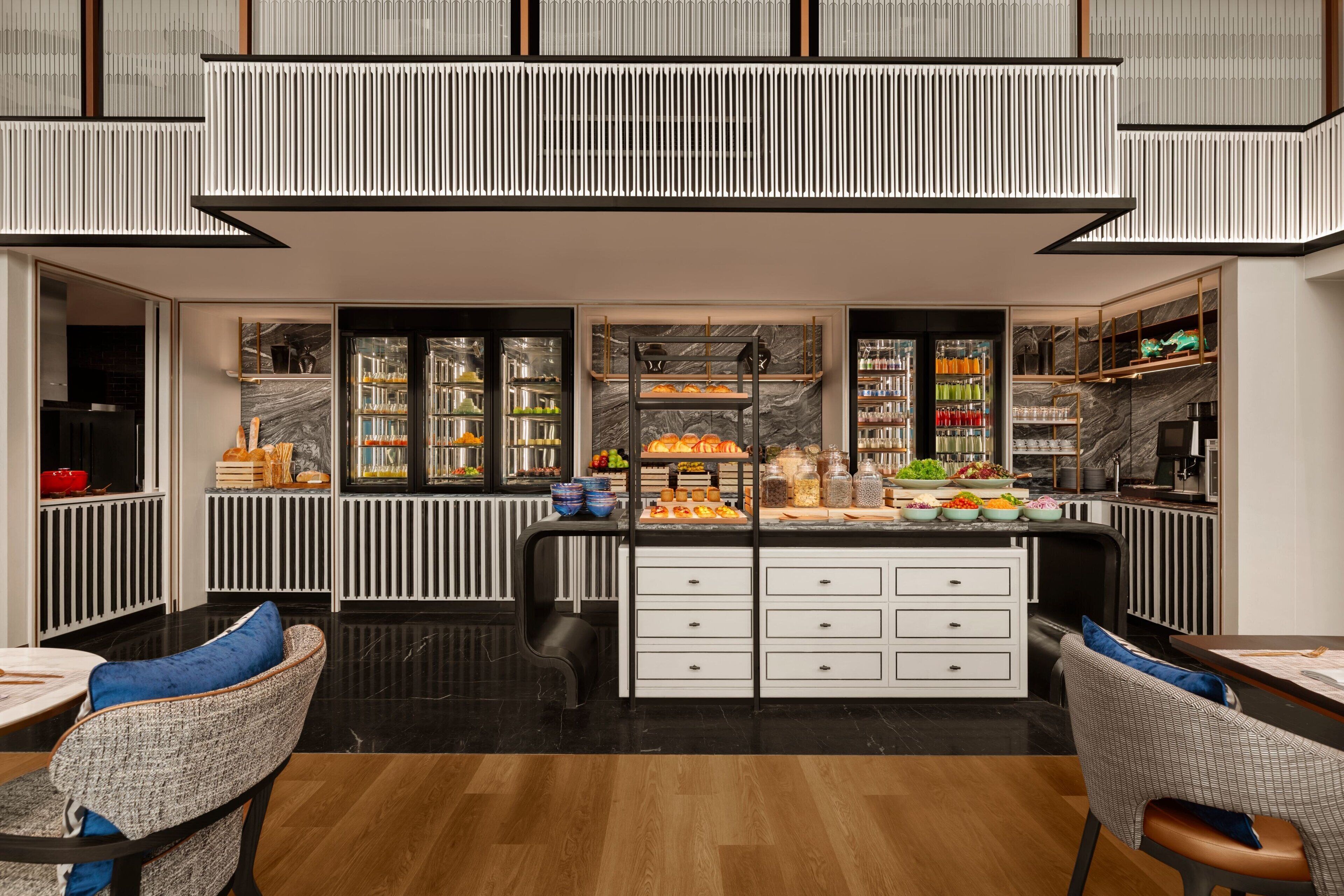 A modern kitchen with a central island, built-in appliances, and a variety of food items displayed on shelves.