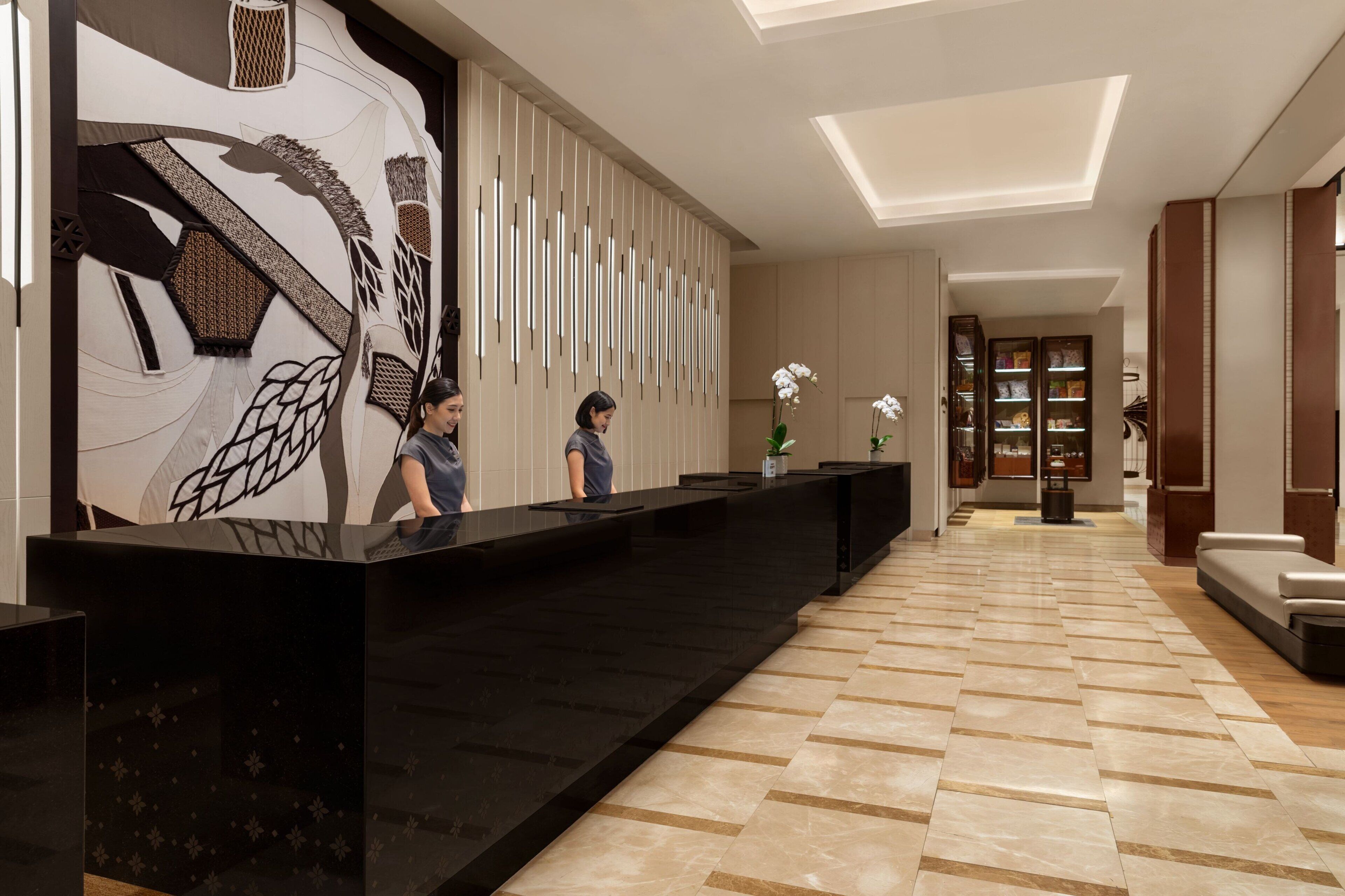 A reception area with a black reception desk, a large abstract wall art piece, and a patterned floor.