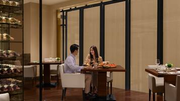 A dining area with a table set for two, a wine rack, and a view through a partition.