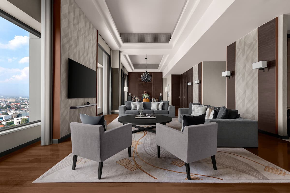 A modern living room with a sofa, two armchairs, a coffee table, and a TV.