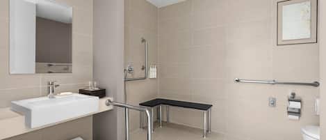Un baño moderno con lavamanos, espejo, toallero, ducha e inodoro.