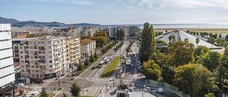 Un paisaje urbano con edificios modernos, una carretera con vehículos y una vista al mar.