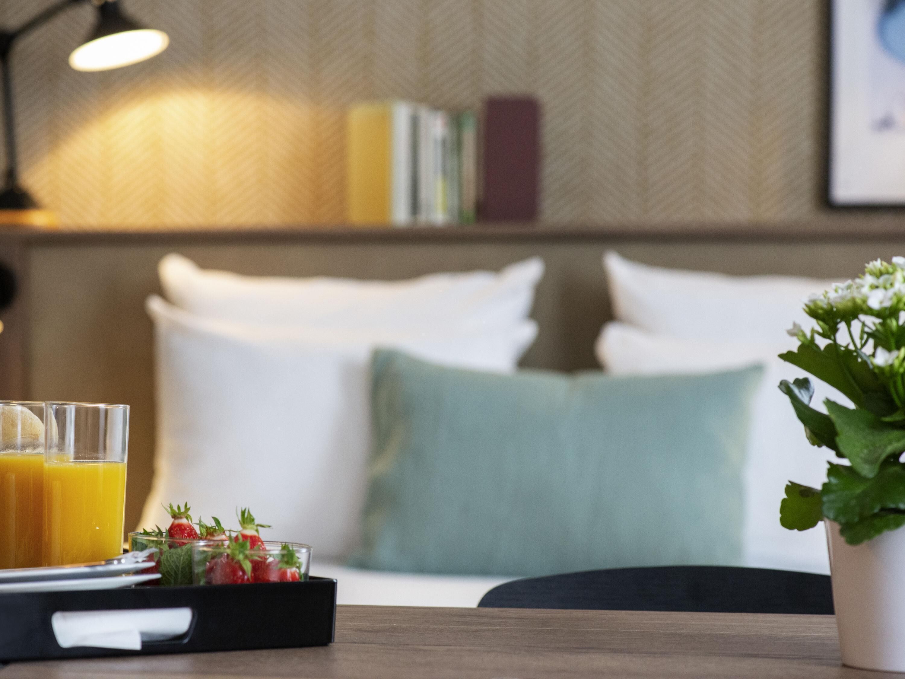 A breakfast table with juice glasses, a fruit tray, and a potted plant.