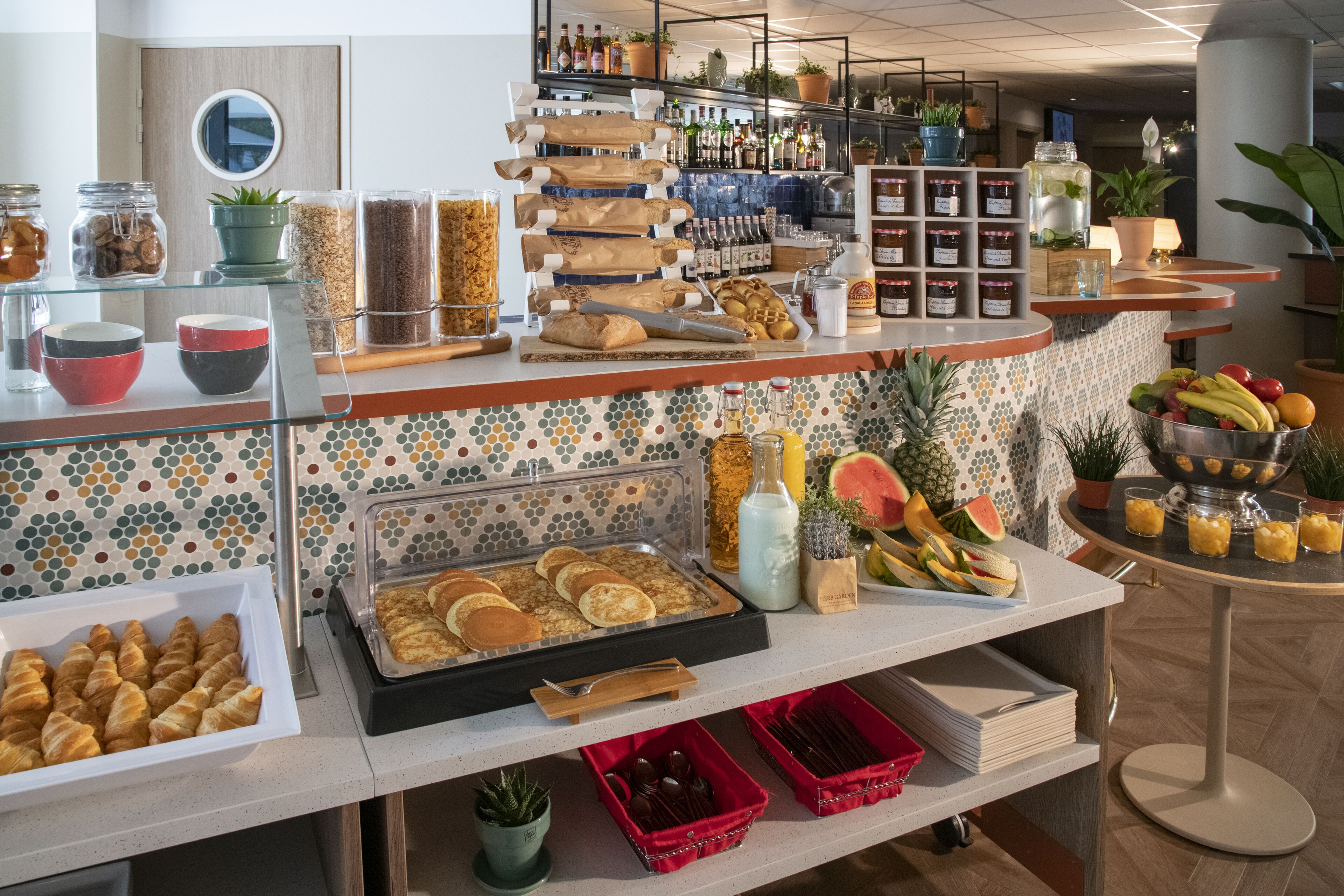 A buffet area with various food items, including pastries, fruits, and condiments.