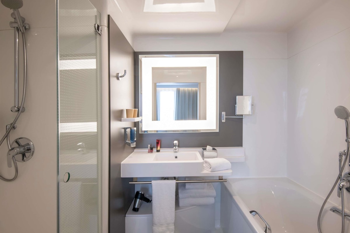 Un baño moderno con cabina de ducha de vidrio, un lavamanos blanco, un espejo y una bañera.