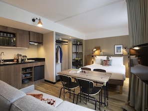 A compact hotel room with a kitchenette, a dining area, a sofa, and a bed. - Novotel Suites Nice Airport (Nice)