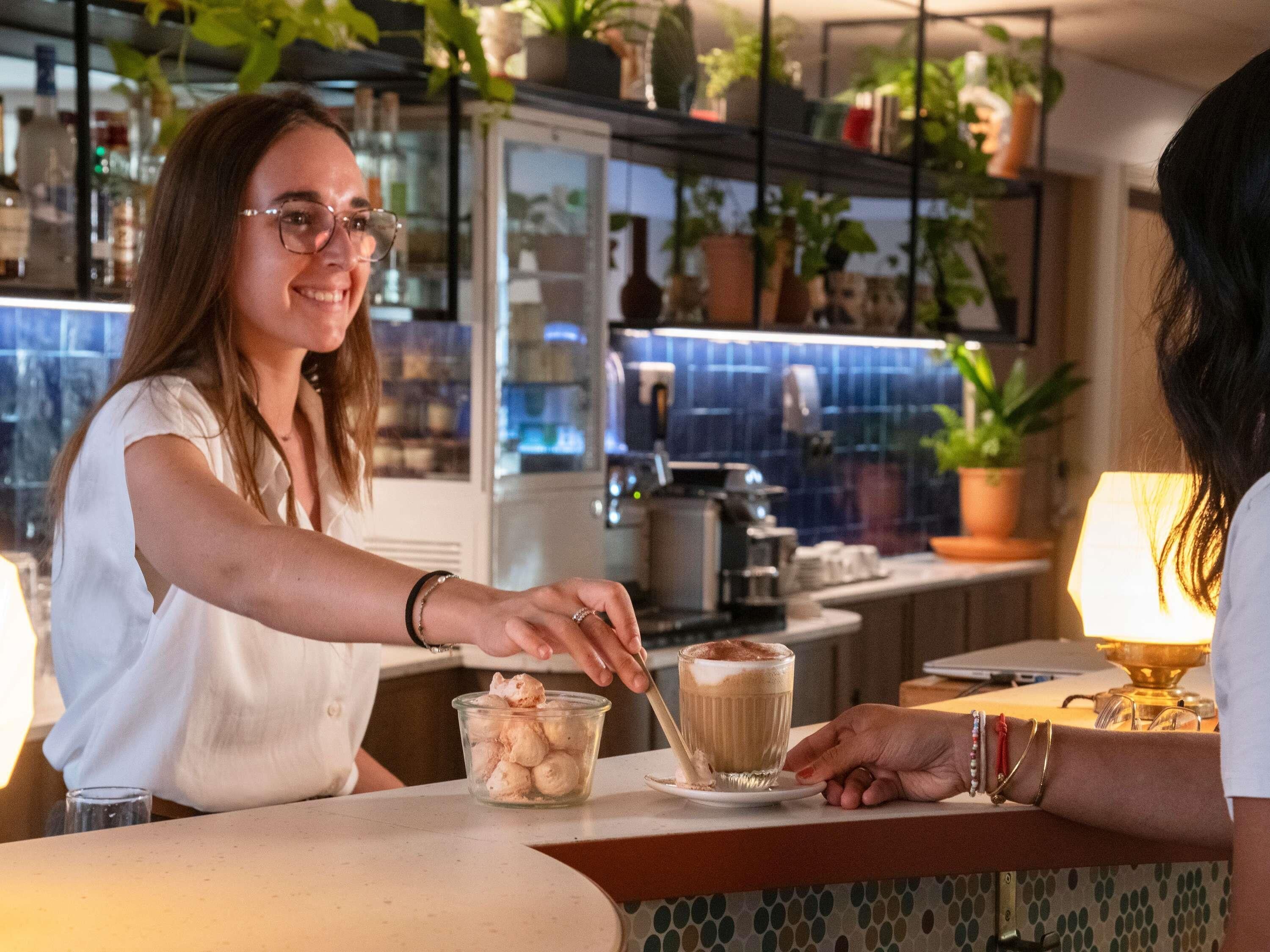 A barista preparing a drink at a counter with a modern kitchen in the background.