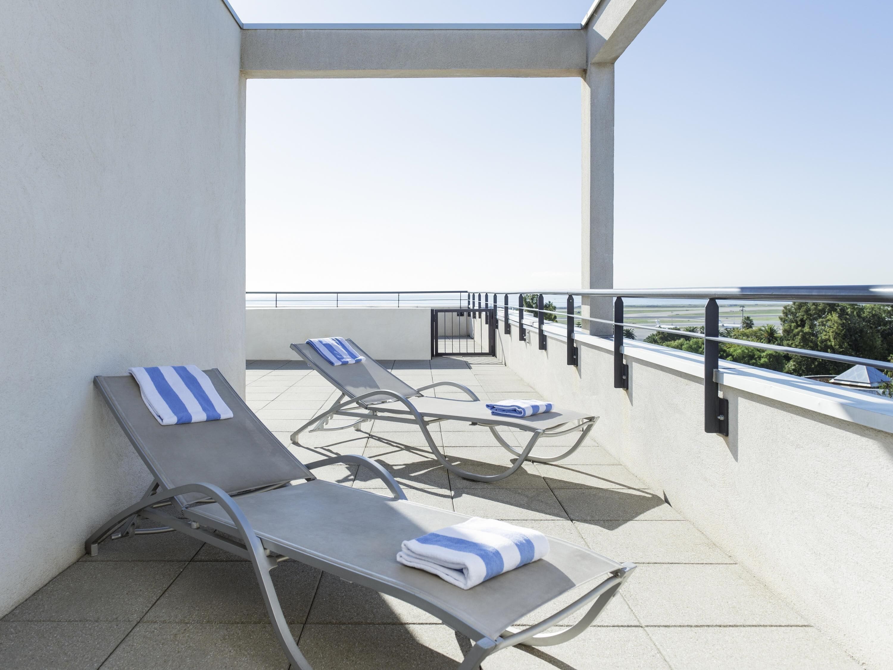 A balcony with two sun loungers, each with a towel.