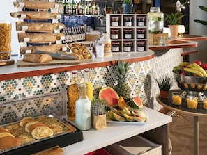 A breakfast bar with various food items, condiments, and a selection of beverages.