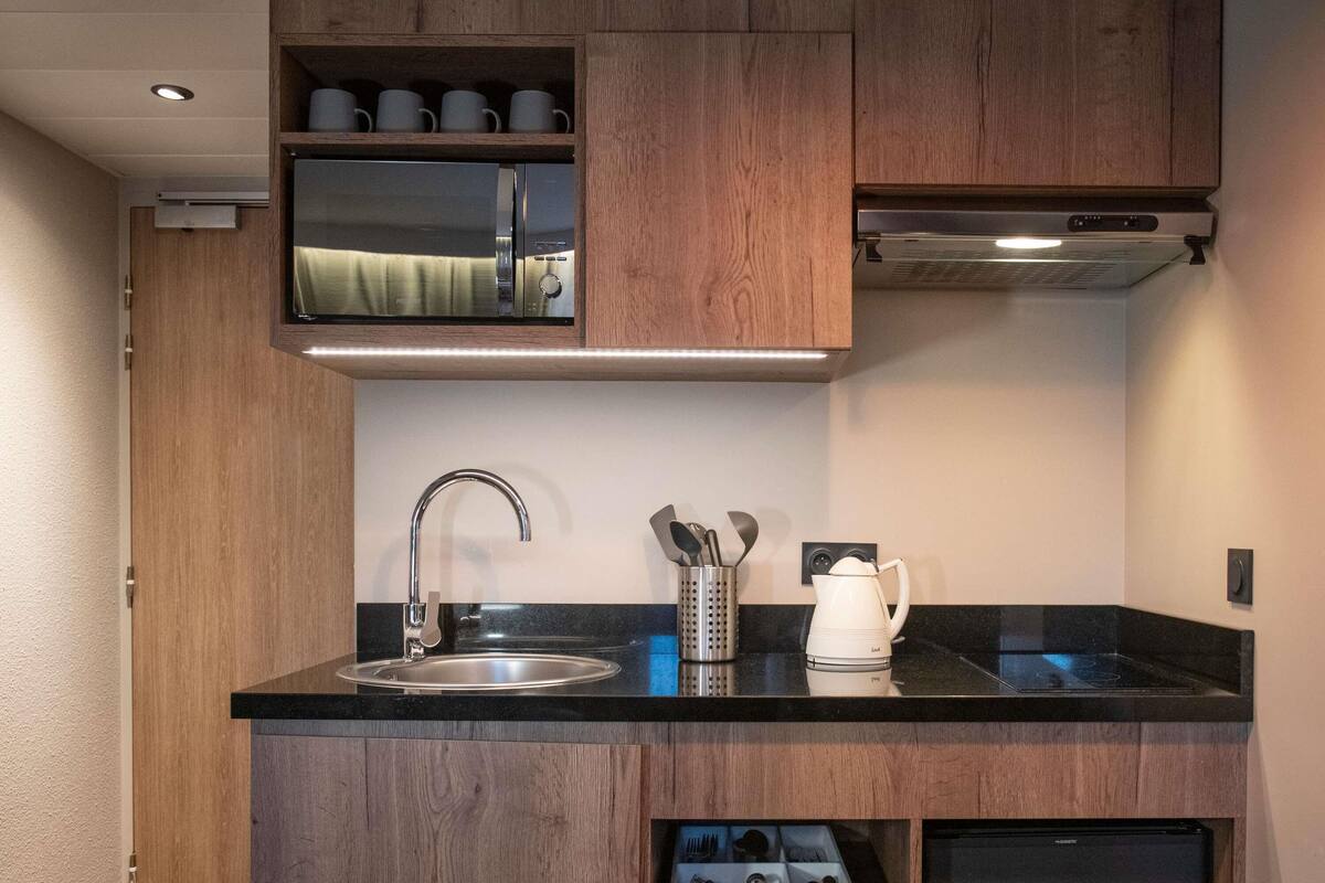 A compact kitchen with a built-in microwave, a sink, and a coffee maker.