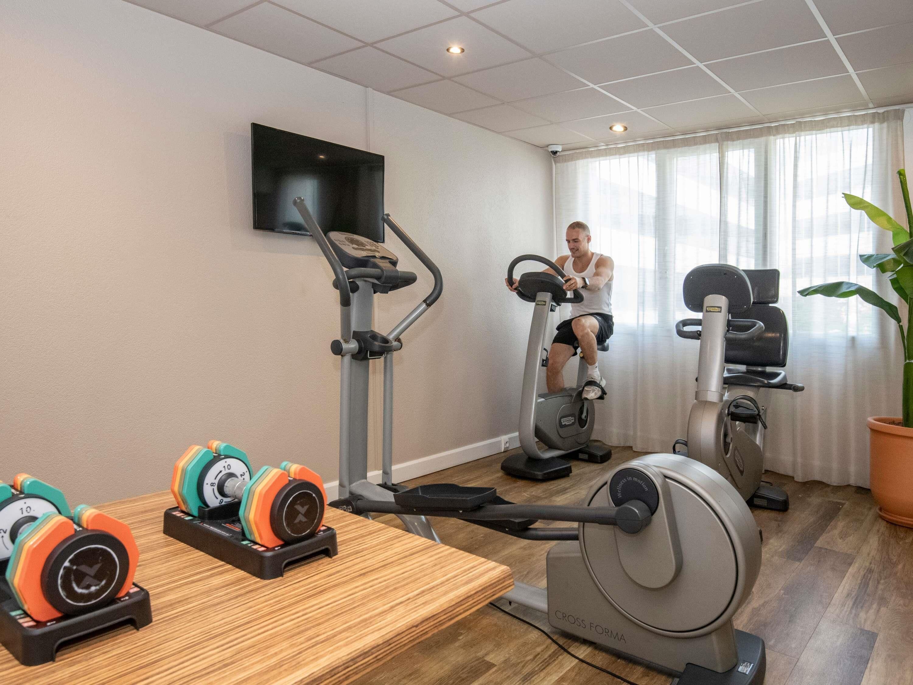 A home gym with exercise equipment, including a stationary bike, elliptical, and weights.