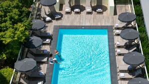 A rooftop pool with lounge chairs and umbrellas, surrounded by greenery. - Novotel Suites Nice Airport (Nice)