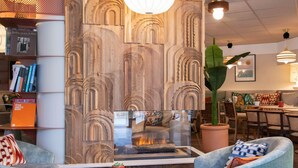 A cozy interior with a wooden wall feature, seating area, and a dining space. - Novotel Suites Nice Airport (Nice)