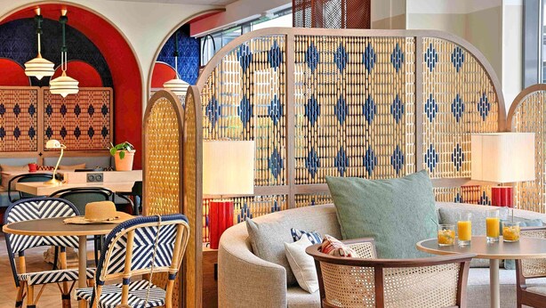 A cozy seating area with a sofa, chairs, and a table, surrounded by decorative bamboo partitions. - Novotel Suites Nice Airport (Nice)