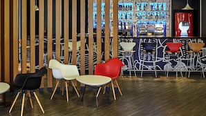 A bar area with wooden partitions, a variety of seating options including chairs and tables, and a bar counter with a coffee machine.
