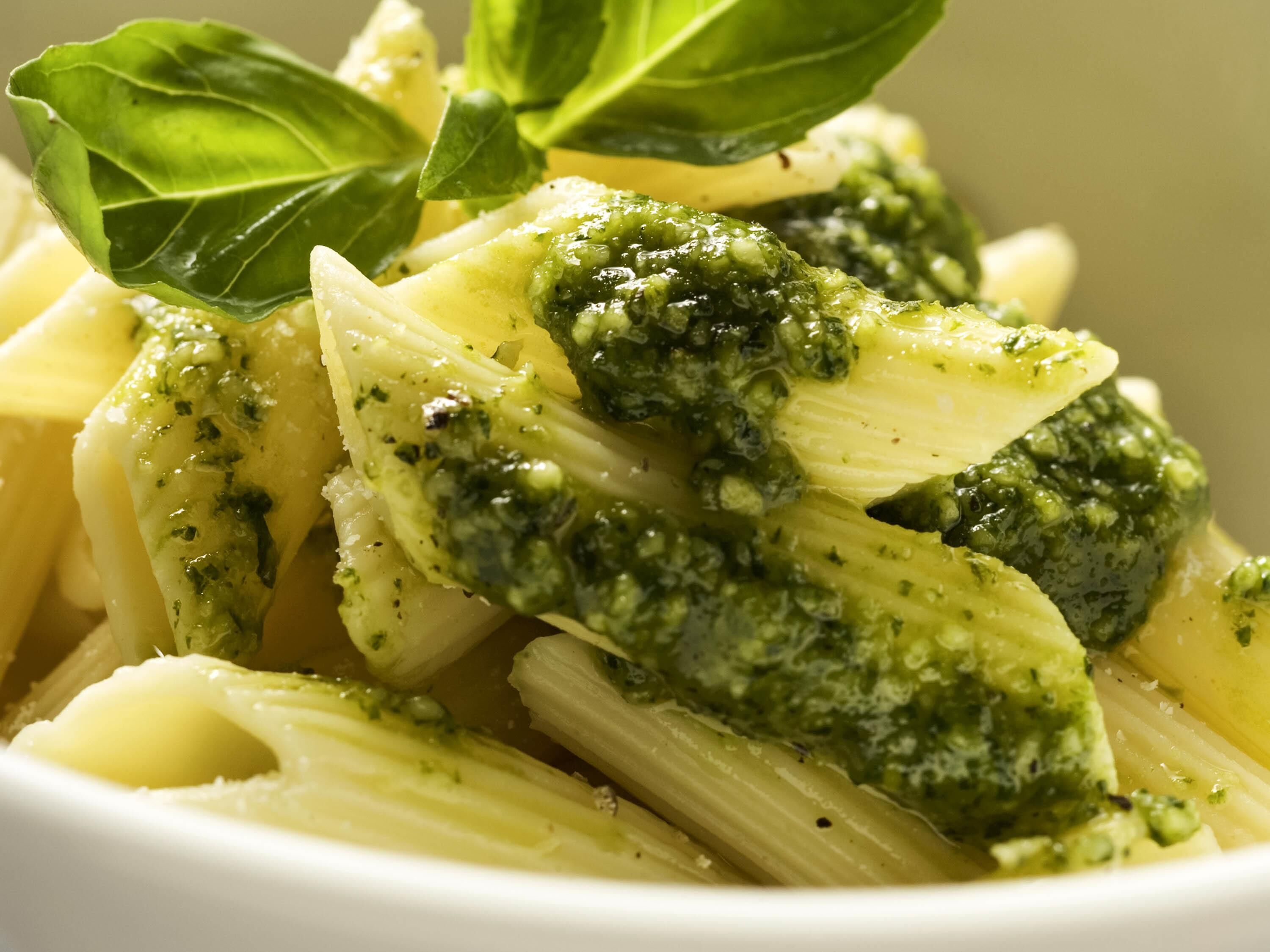 Un plato de pasta con salsa verde y hojas de albahaca.