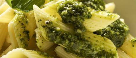 Un plato de pasta con salsa verde y hojas de albahaca.