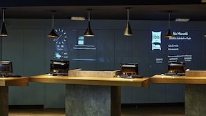 A modern hotel reception area with three reception desks, each equipped with a coffee machine and a computer.