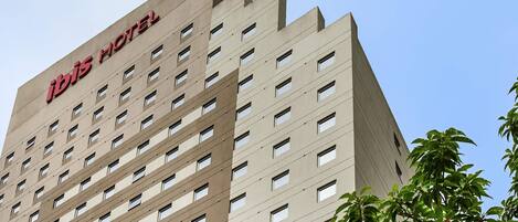 Un edificio hotelero de gran altura con un diseño arquitectónico moderno, con numerosas ventanas y una señalización destacada en la parte superior.