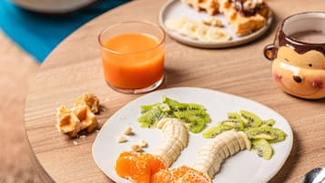 Uma mesa de madeira com uma travessa de frutas, um copo de suco de laranja e uma xícara de café.