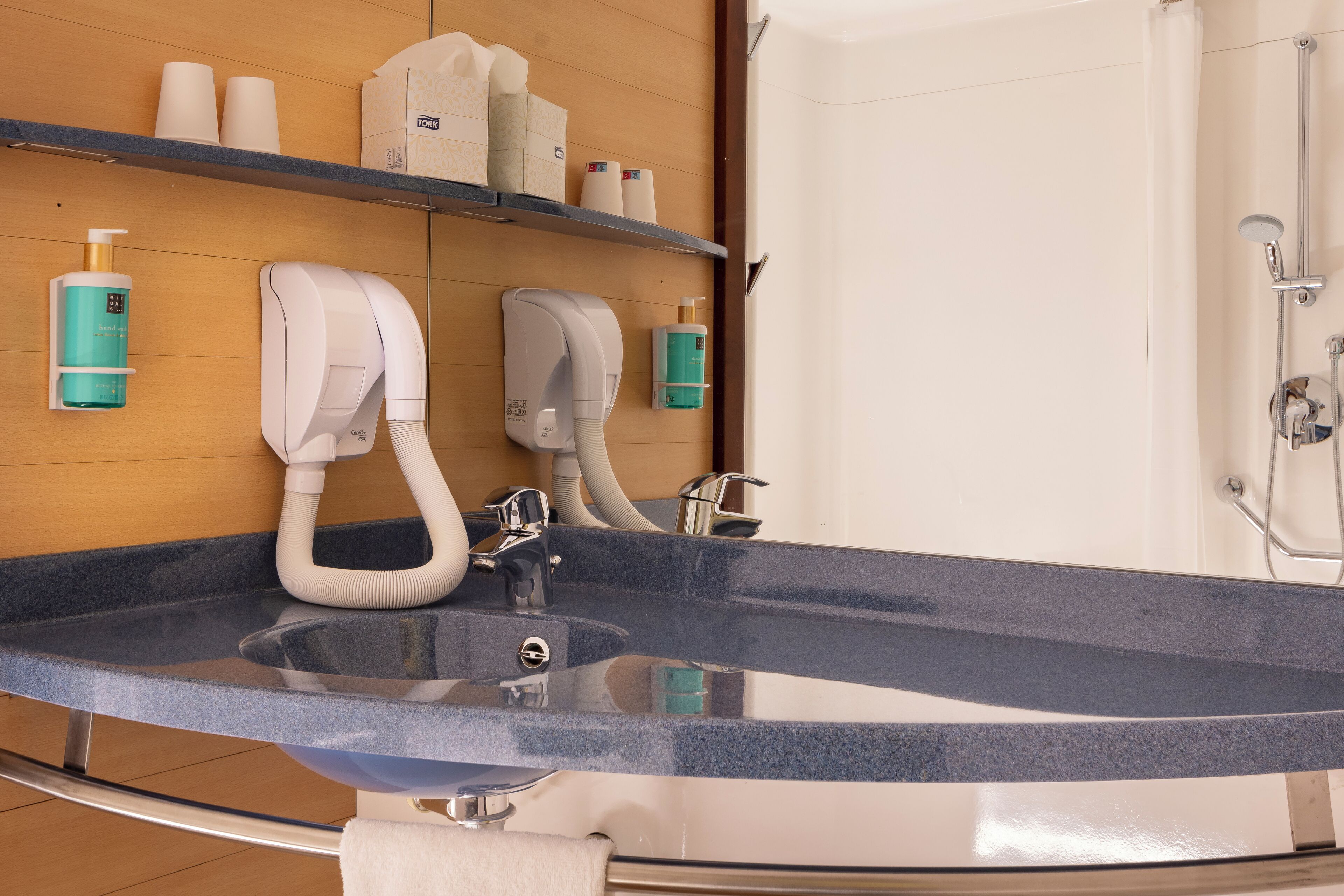 Un bagno moderno con un lavandino grande, portasci asciugamani ed scaffali con articoli da toilette.
