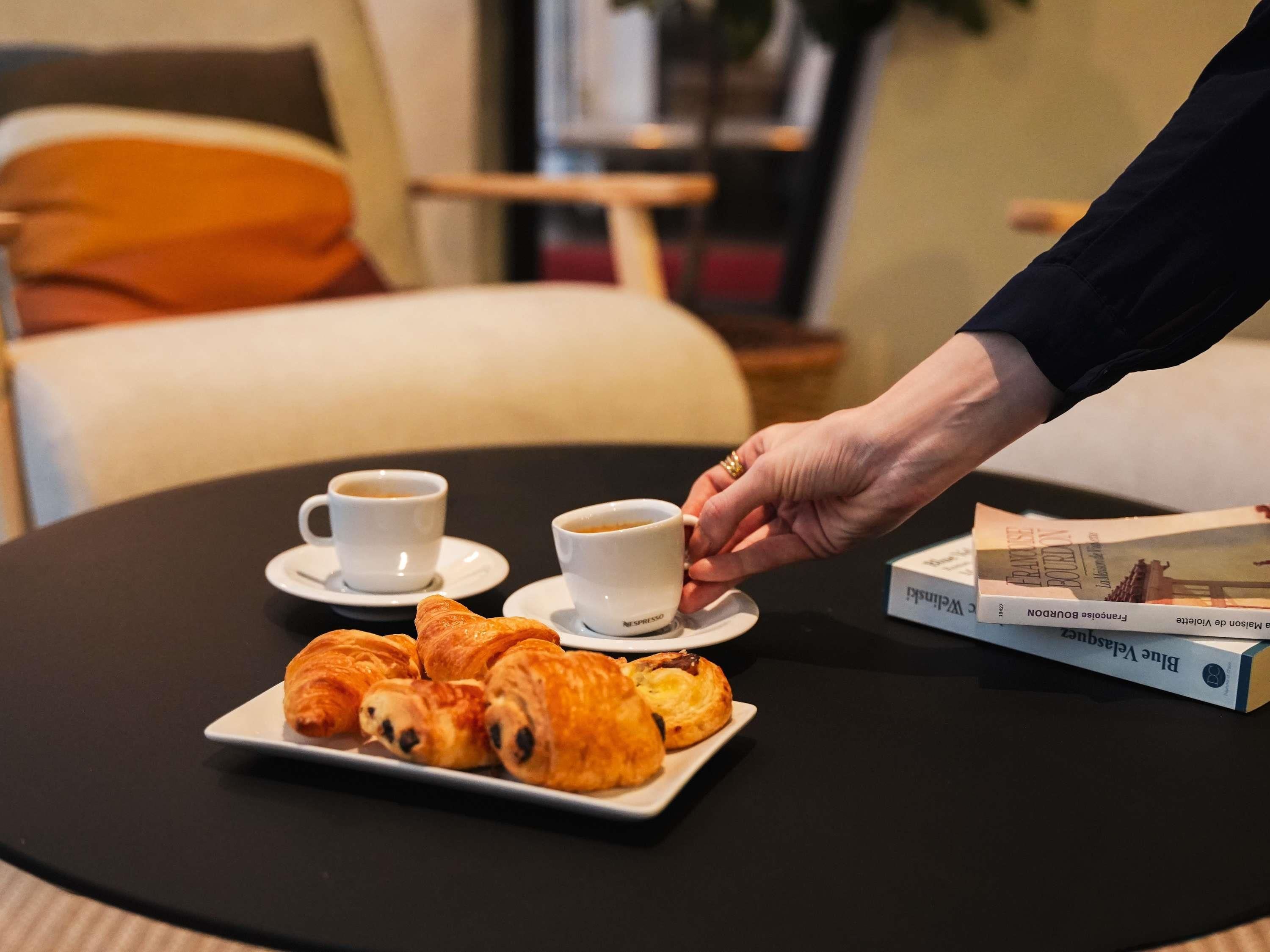 Ett bord med croissanter, två koppar kaffe och en bok.