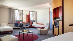 Una habitación de hotel con cama, escritorio, silla, sofá y microondas.