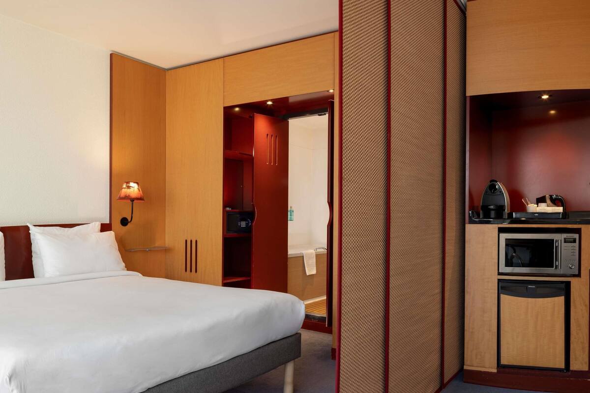 Ein Hotelzimmer mit Bett, Mikrowelle, einer kleinen Küchenzeile und einem begehbaren Kleiderschrank.