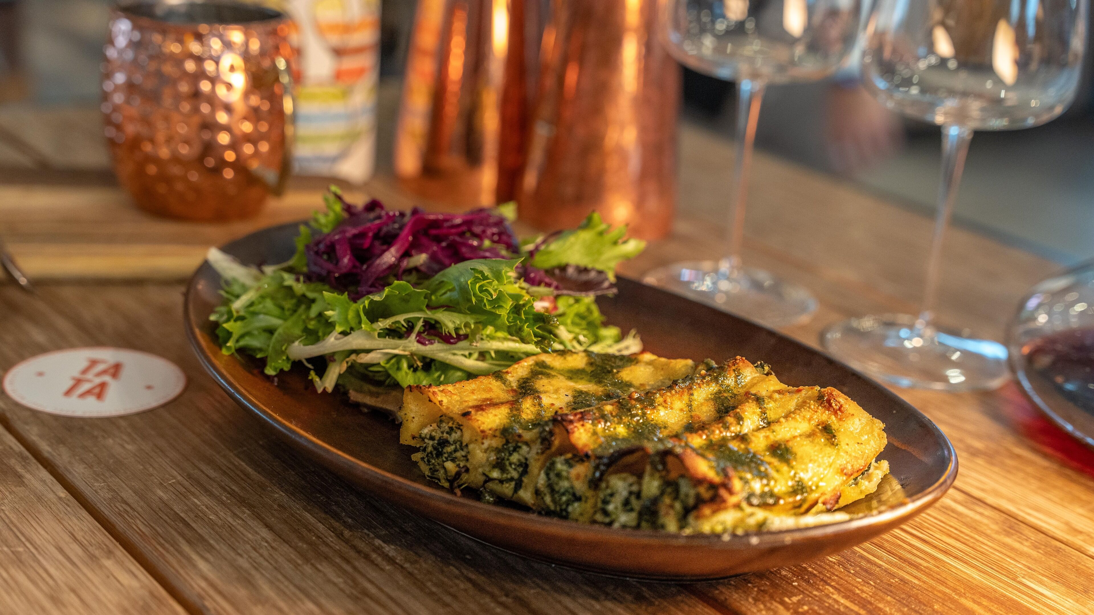 A plate of food with a salad and a glass of red wine on a wooden table.