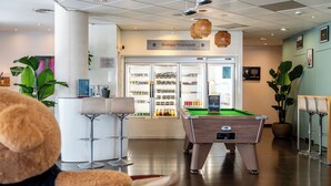 Una mesa de billar, un área de bar y una vitrina refrigerada con diversas bebidas.
