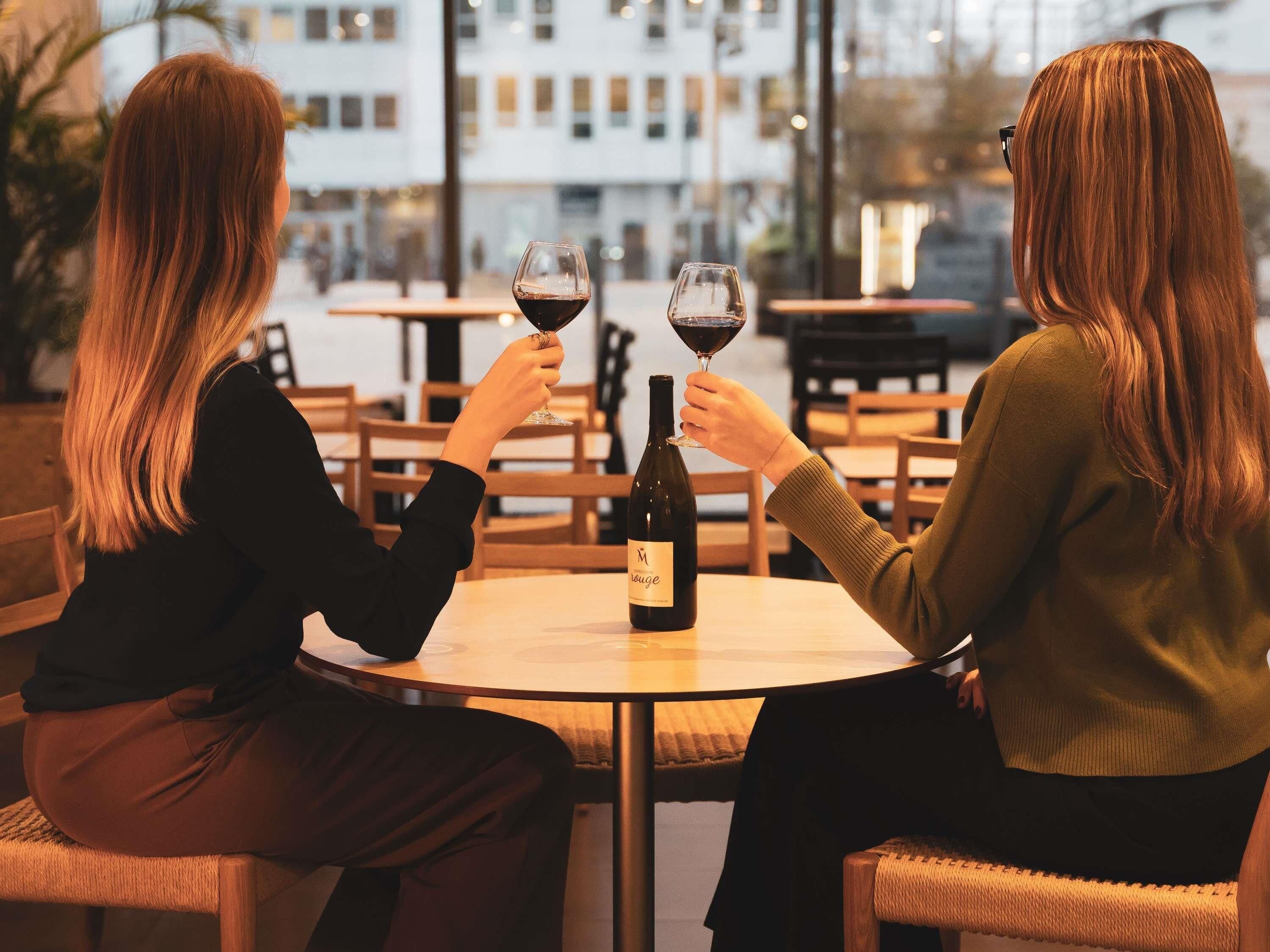 Dos personas sentadas en una mesa redonda con una botella de vino y copas.
