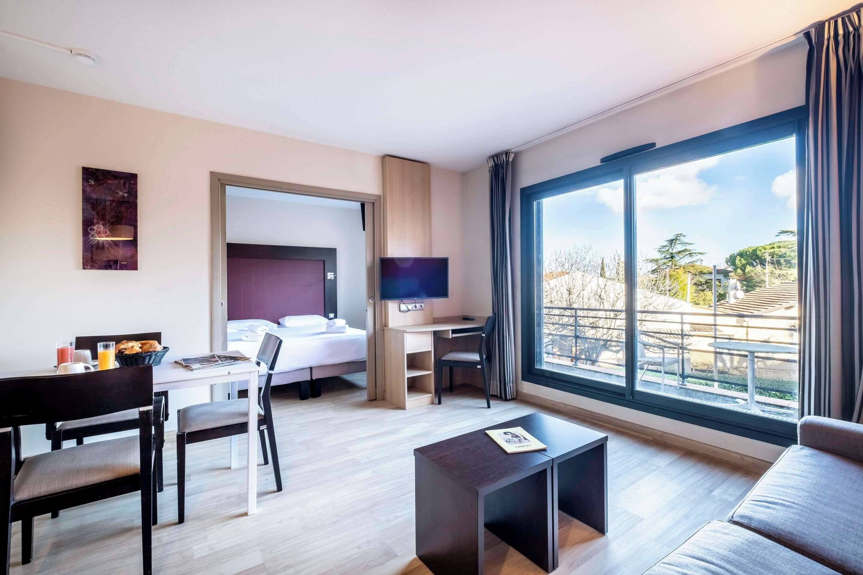 Una habitación de hotel moderna con cama, escritorio y ventana grande.