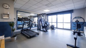 A gym with a treadmill, weight machines, and a large window.