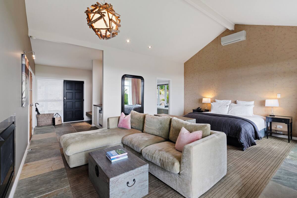 Une chambre d’hôtel moderne dotée d’un grand lit, d’un canapé, d’une table basse et d’un lustre original.