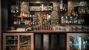 Zona de bar con estantes llenos de botellas de licores y vasos.