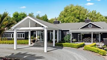 A two-story building with a covered entrance, a patio area, and a landscaped garden.