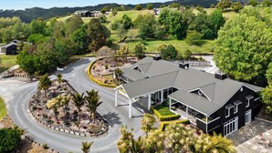 A modern two-story building with a covered driveway and landscaped garden. - Woodhouse Mountain Lodge (Warkworth)