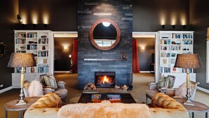 A modern living room with a fireplace, two sofas, a coffee table, and two side tables with lamps. - Woodhouse Mountain Lodge (Warkworth)