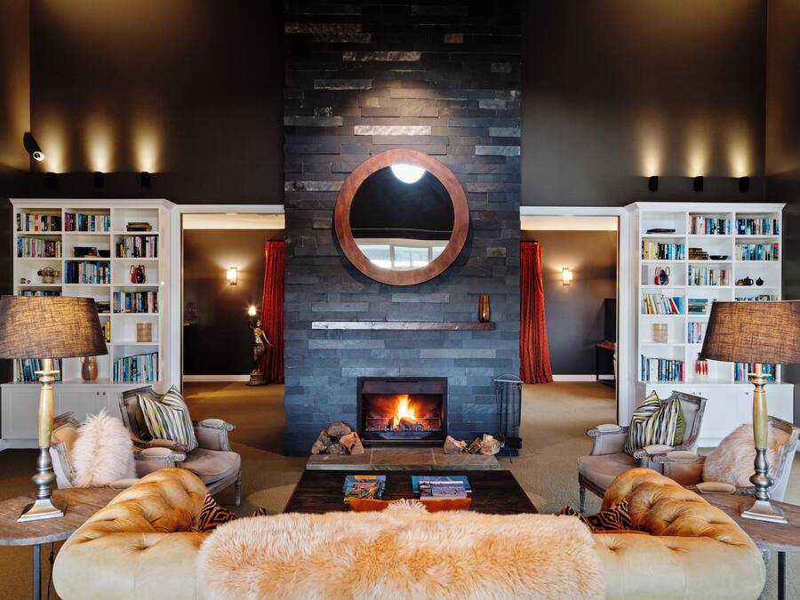 Una sala de estar moderna con chimenea, dos sofás, una mesa de centro y dos mesitas de noche con lámparas.