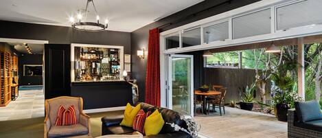 Un vestíbulo de hotel moderno con un sofá de cuero negro, una silla de madera y una zona de bar.
