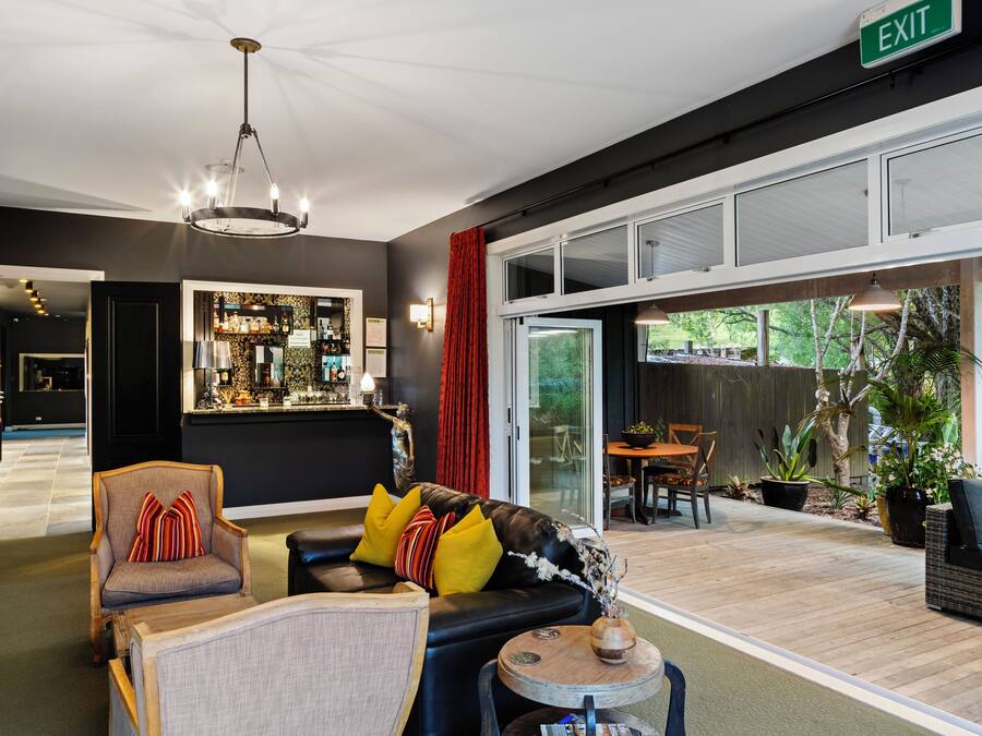 A modern hotel lobby with a black leather sofa, a wooden chair, and a bar area.