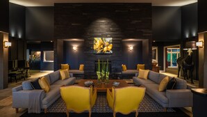 A modern living room with a dark stone fireplace, two sofas, a coffee table, and a large painting above the fireplace. - Woodhouse Mountain Lodge (Warkworth)