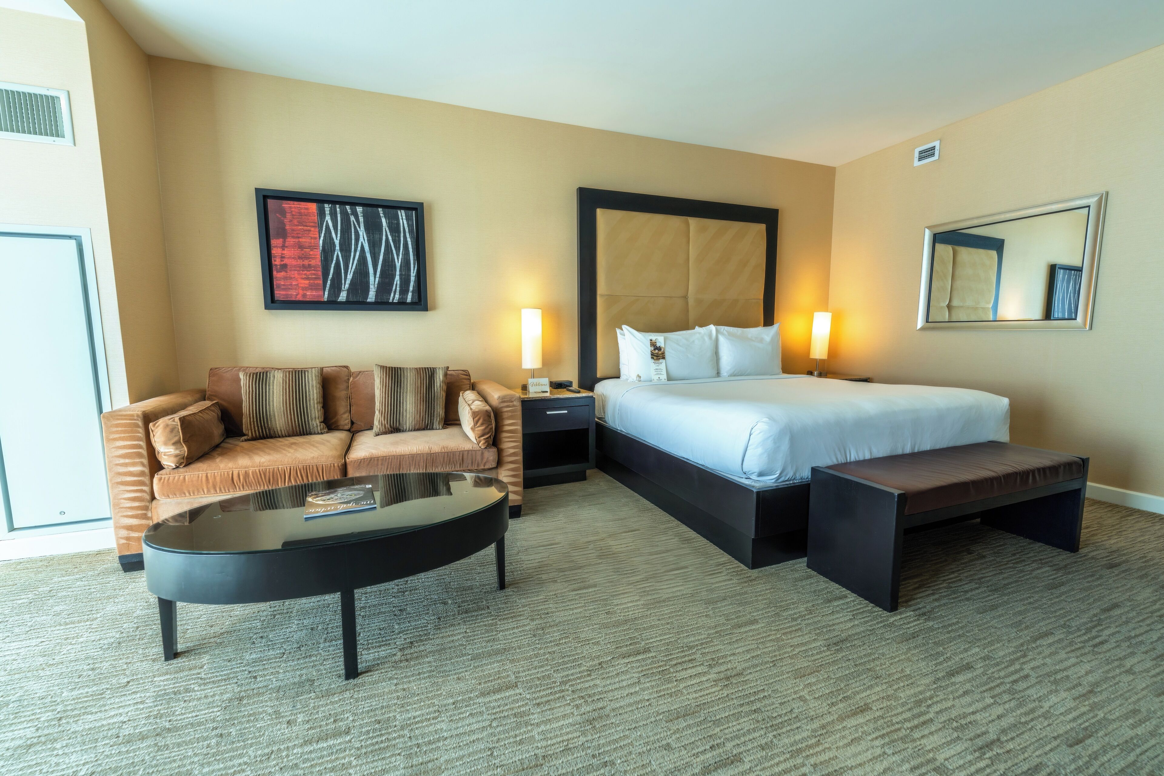 Ein Hotelzimmer mit einem Bett, einem Sofa, einem Couchtisch und einer Bank.