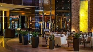 A modern indoor dining area with a restaurant named "Steakhouse" in the background, featuring a stone wall and a ceiling with a geometric pattern. - Agua Caliente Casino Rancho Mirage (Rancho Mirage)